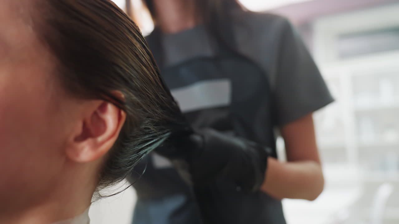 스타일리스트가 시술을 하고, 헤어 케어 제품을 전문적으로 사용하며, 숙련된 스타일리스트가 젖은 머리카락에 제품을 빠르게 바르고, 숙련된 미용사가 촉촉한 모발에 트리트먼트를 고르게 빠르게 도포합니다.