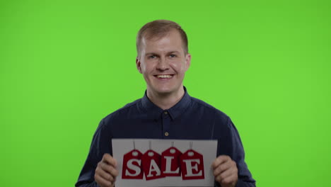 cheerful blonde guy showing sale word advertisement. online shopping with low prices on black friday