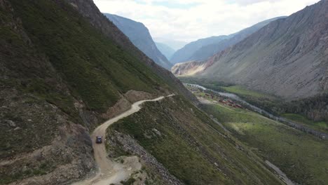vista aérea de un suv negro conduciendo a lo largo de una carretera peligrosa y empinada