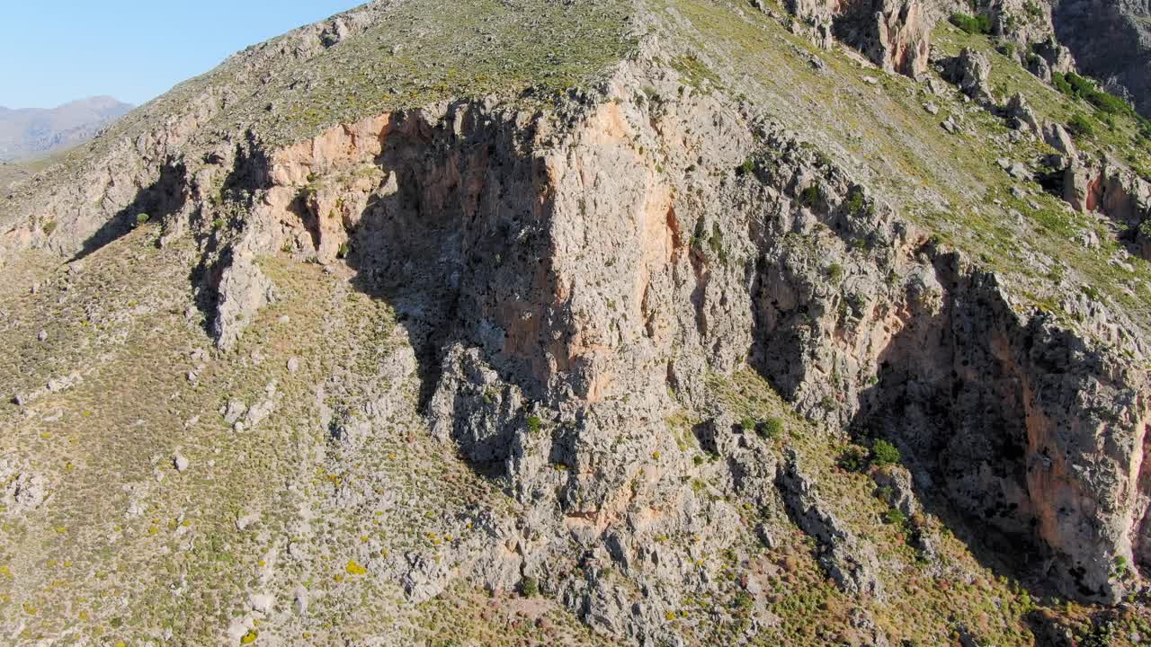 Drone closing up on a mountainside, rocky hill with the cliff