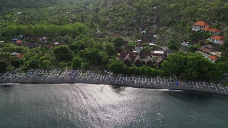 Drone-panning-along-a-beach-showing-many-traditional-fishing-boats-and-the-village-behind-the-beach