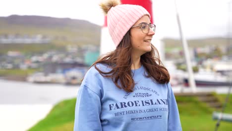 young woman smiles looking at the camera wearing a faroese blue jumper, torshavn