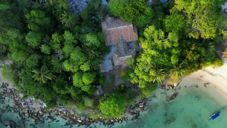 Vuelo-Vista-Aérea-De-Una-Cabaña-En-Una-Península-De-Lenguado-Tropical-Con-Agua-Turquesa-Y-Exuberante-Vegetación-Verde