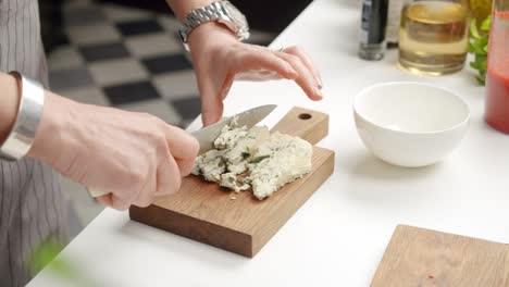 Crop-chef-cutting-blue-cheese-on-board