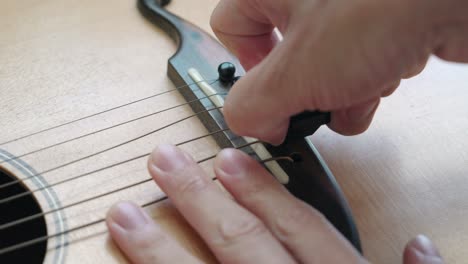 manos quitando los pines del puente de una guitarra acústica - cerrar