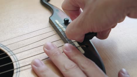 hands removing bridge pins of an acoustic guitar - close up