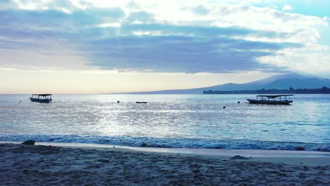 Ruhige-Bucht-Mit-Traditionellen-Indonesischen-Booten-Jukung-Bei-Sonnenuntergang-Mit-Blauem-Staubigen-Himmel-Mit-Flauschigen-Wolken-über-Dem-Berghorizont-In-Bali