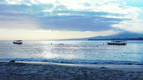 bahía tranquila con jukung de barcos tradicionales indonesios al atardecer con cielo azul polvoriento con nubes esponjosas sobre el horizonte de las montañas en bali