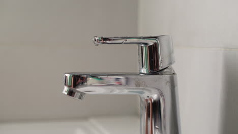 Young-woman-washes-hands-under-running-water-in-bathroom