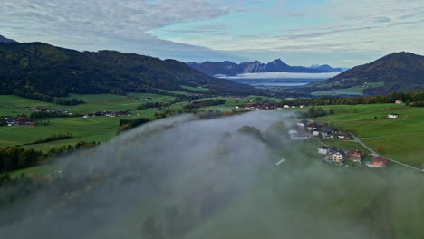 aerial view backwards over the foggy countryside of attersee, fall day in austria