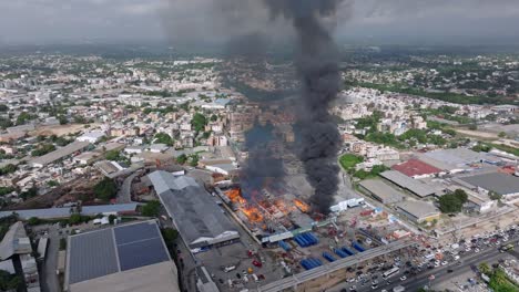 Dense-column-of-black-smoke-of-burning-warehouse-on-fire,-Santo-Domingo