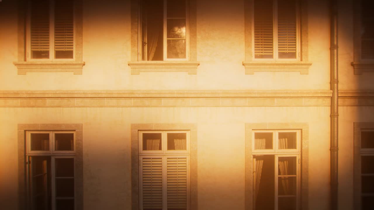 Luce solare in movimento che attraversa la facciata di un edificio a più piani sulla strada, proveniente dal sole a bassa angolazione, rivelando le finestre.