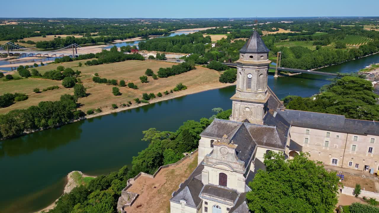 Abbey Church of Saint-Florent-le-Vieil overlooking Loire River, Pont de Varades bridge in background, France . Aerial drone forward