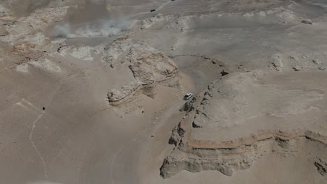 Aerial-Shot-of-Trucks-driving-through-a-canyon-in-the-dessert