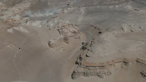 Toma-Aérea-De-Camiones-Conduciendo-A-Través-De-Un-Cañón-En-El-Desierto