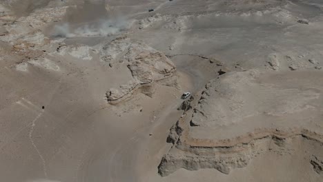 fotografía aérea de camiones conduciendo a través de un cañón en el desierto