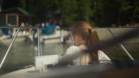 little girl with spine brace leans out open hatch on motorboat deck on sunny day. schoolgirl rests on modern yacht in ocean port on holiday