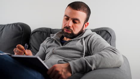 un hombre caucásico del medio oriente escribiendo notas en su diario - de cerca