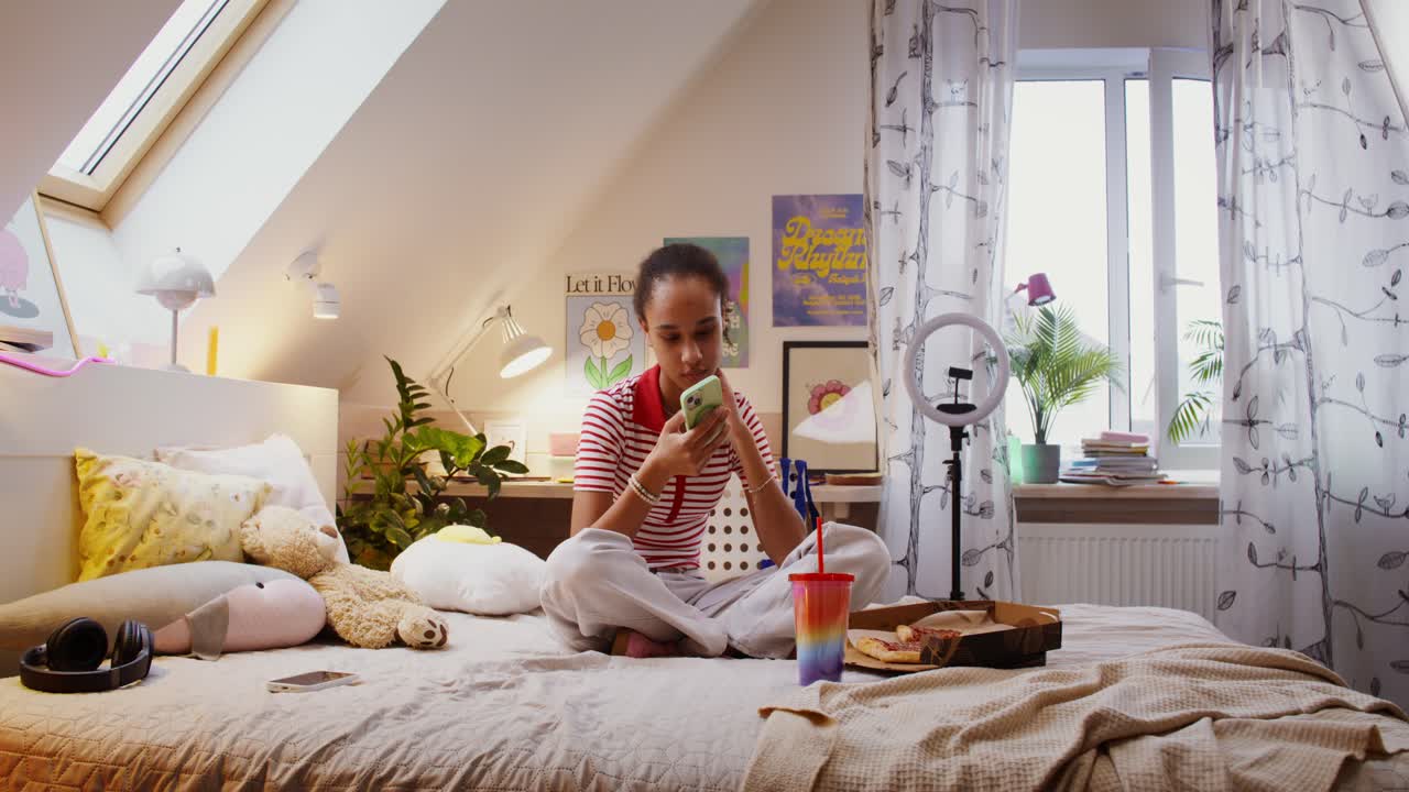 chica adolescente en el dormitorio usando el teléfono con pizza y bebida