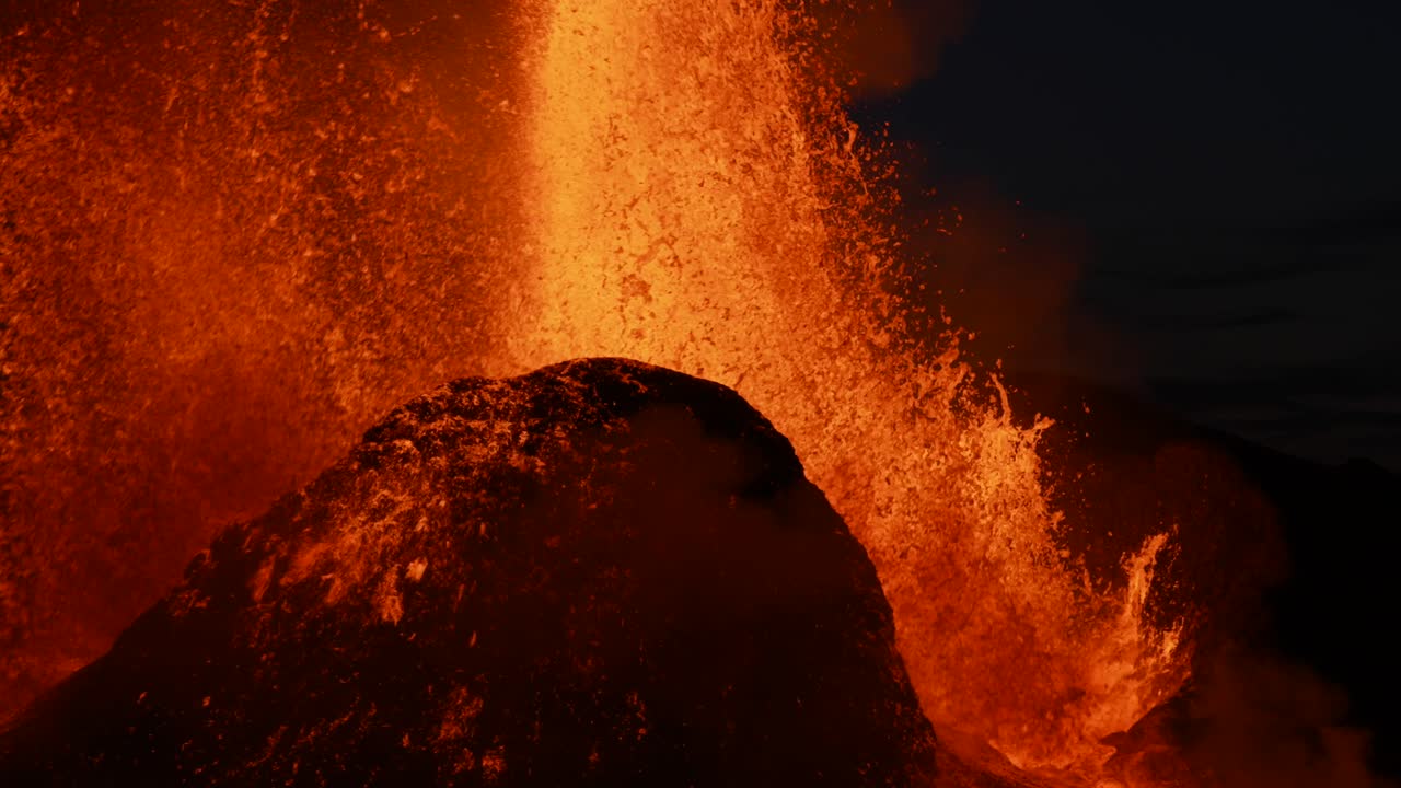 Slow motion Close up of exploding and spewing lava of volcano crater at night