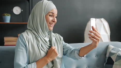 woman wearing hijab taking a selfie on her phone