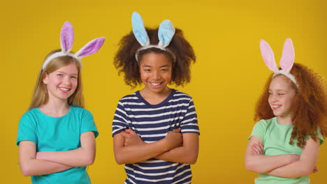 studio portrait shot of three children friends wearing rabbit ears standing against purple background