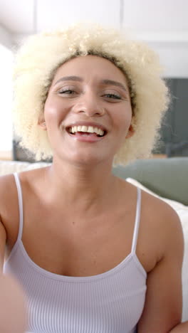 vertical video: smiling woman with curly hair relaxing at home, enjoying leisure time indoors