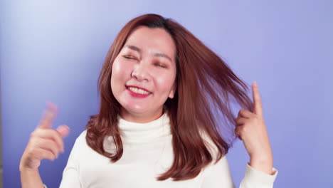 보라색 배경-3에 고립된 휴식 실내 스튜디오 촬영과 함께 젊은 아시아 쾌활한 여성 장난 음악 댄스