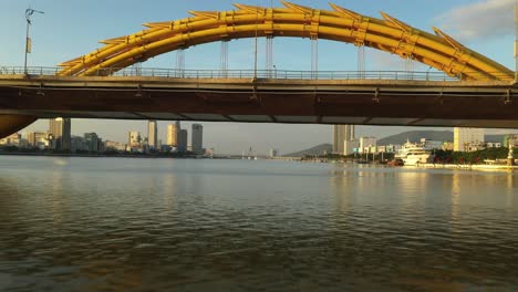 aerial of flying underneath dragon bridge with danang city scape in the background