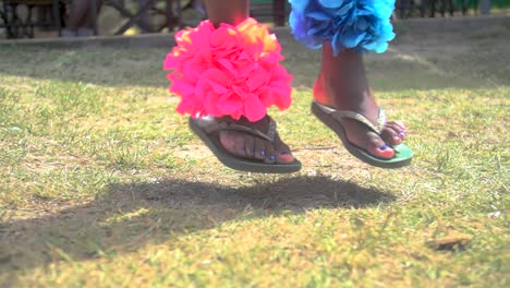 feet in sandals jumping dancing on the grass with festive colorfull decorations on the legs, slow motion