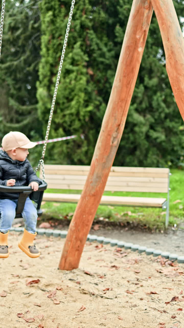 Un bambino si dondola su un'altalena in un parco cittadino. Un bambino piccolo gioca in un parco giochi. Bambino a passeggio nel parco in autunno.