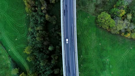 aerial view over a busy highway road in france. only grass fields and trees around the roads. cars and trucks driving on the roads under the sun.