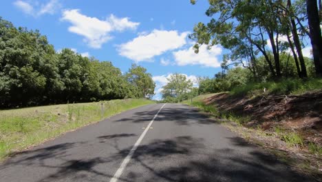 rear facing driving point of view pov of a deserted queensland country road with view of mt coonowrin - ideal for interior car scene green screen replacement