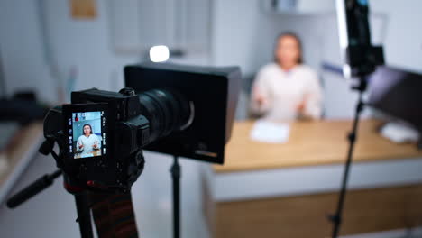 approaching camera display with the woman speaking and gesturing. blog content creation. blurred backdrop.