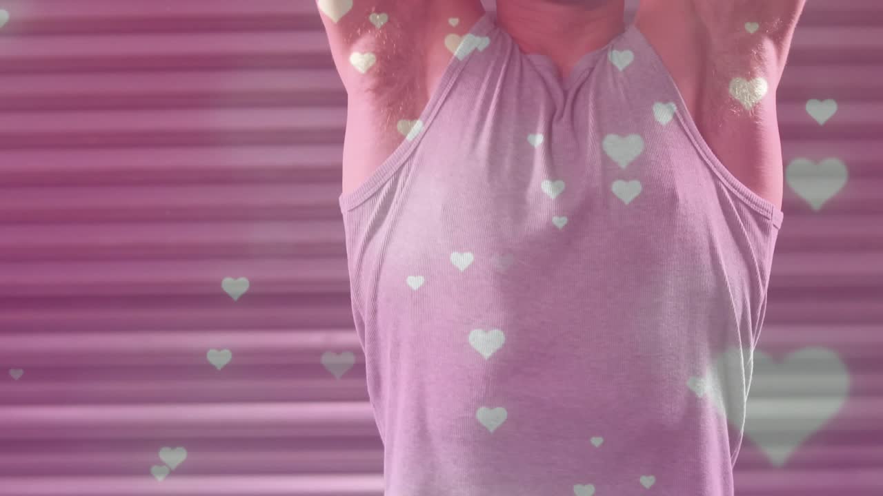 Man raising arms then pressing kettlebells overhead in gym, pink hearts floating for strength