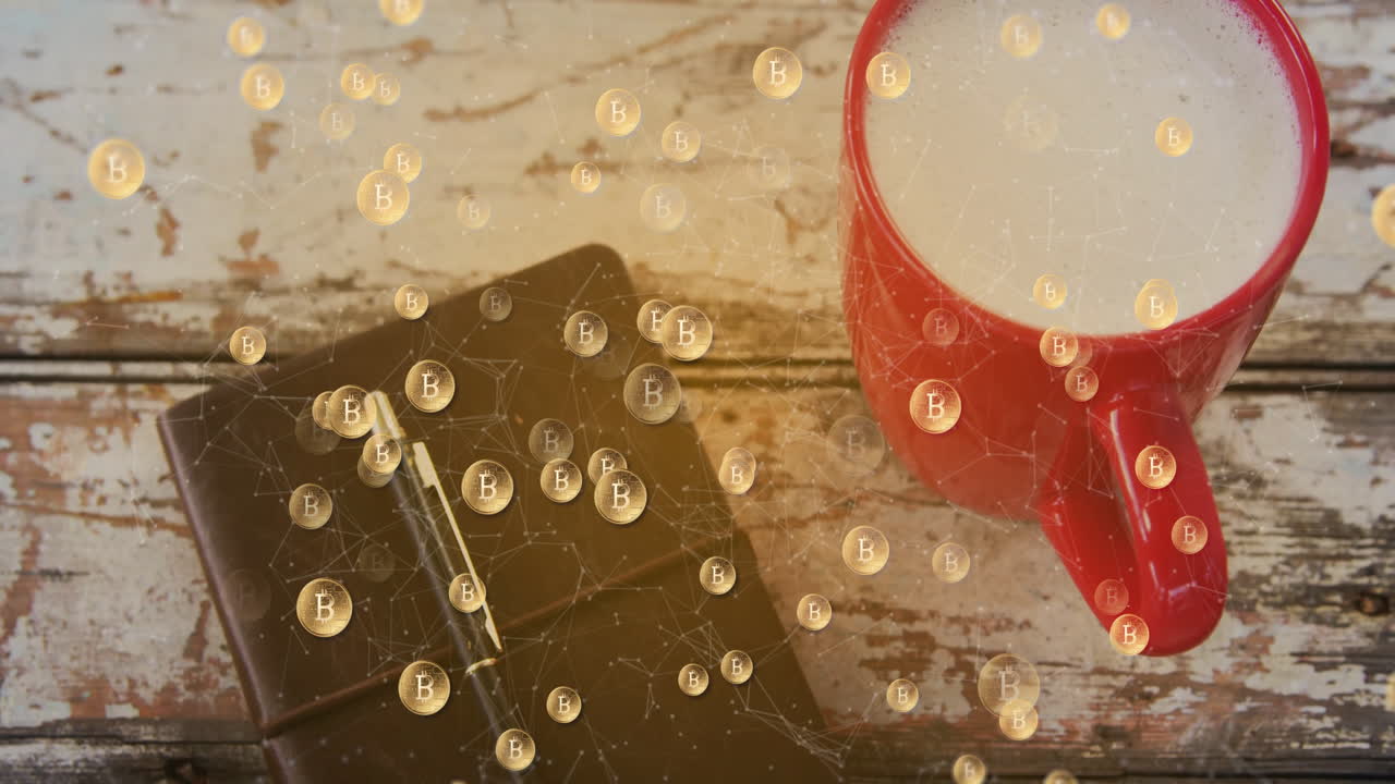 Red coffee mug sitting on wooden table beside black notebook showing flat design Bitcoin icons