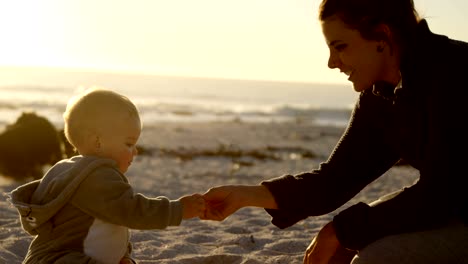 mother playing with her baby boy in the beach 4k