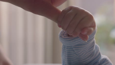 mother holding baby hand touching fingers nurturing newborn caring for infant at home enjoying motherhood