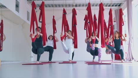 ladies practice modern fly yoga and stand in warrior pose