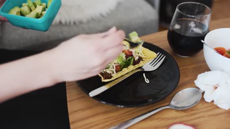 Putting-some-avocado-on-vegan-minced-soy-meat-laying-on-a-hard-shell-tortilla