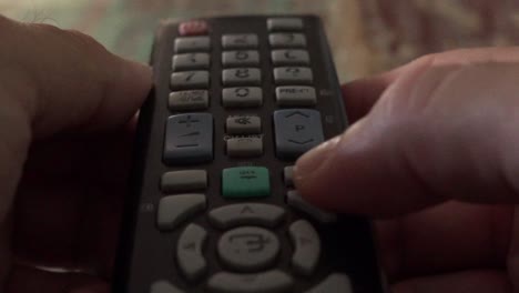 Close-up-on-man's-hands-pushing-buttons-on-an-old-tv-remote-control-120fps