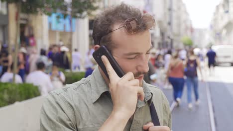 Young-man-talking-on-the-phone-in-the-crowded-street.