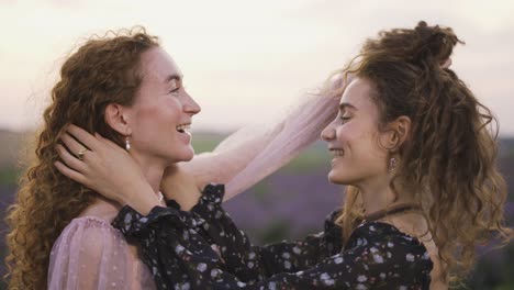 two beautiful curly girls combing together their hair outdoors