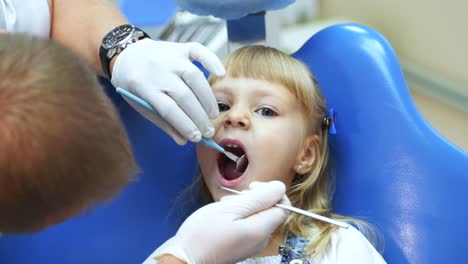 dentist in white gloves examines the teeth of a little girl in a dental clinic. Treatment of caries in children