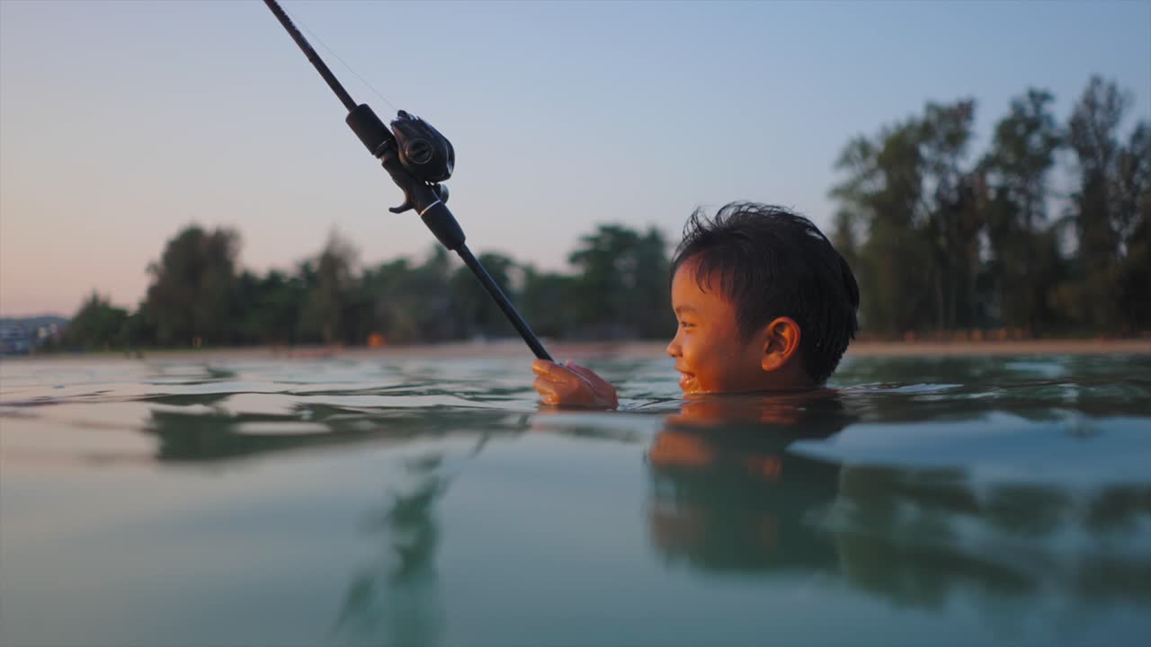 Young boy fishing in the ocean at sunset