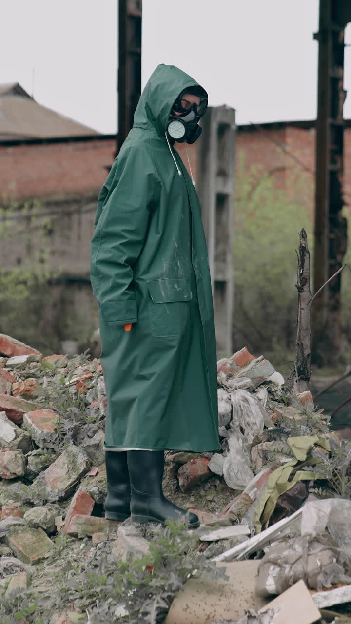 Survivor in destructed place. Human in protective clothing and respirator standing on a pile of garbage in abandoned place. High level of radiation. Vertical video
