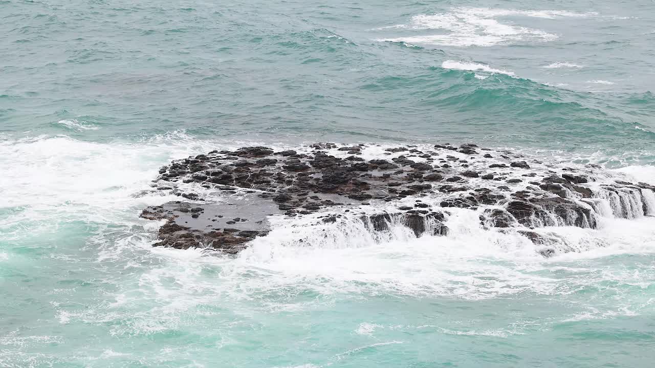 Dynamic ocean waves crash against a rocky outcrop, captured in natural light along Australia's scenic Great Ocean Road