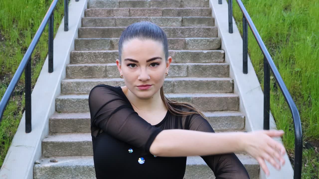 매력적인 여성 댄서가 계단 앞에서 포즈를 취합니다.