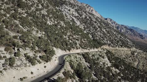 Tracking-Aerial-View-of-Car-on-Hillside-Road-Under-Rugged-Slopes-of-Mount-Whitney,-Sierra-Nevada,-California-USA