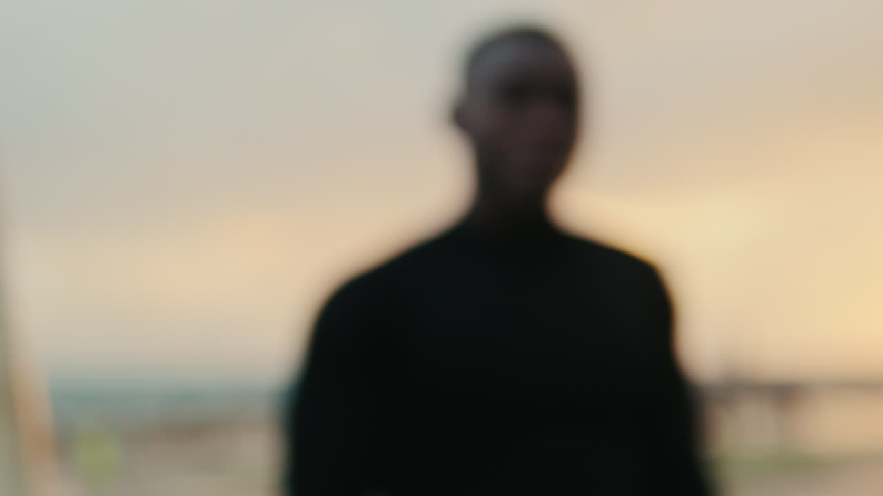 Contemplative Young Black Man Standing by the Water at Sunset